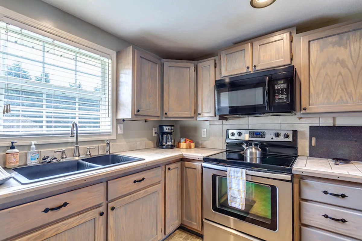 A cozy kitchen setup with a sink, stove, microwave, and coffee maker. The layout emphasizes practicality and warmth, with enough space for baking, meal preparation, and relaxed social interactions. The details suggest a functional, family-friendly environment.